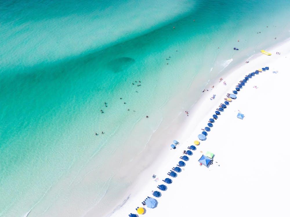 Stunning aerial view of Santa Rosa Beach showcasing turquoise waters and colorful umbrellas, perfect summer destination.