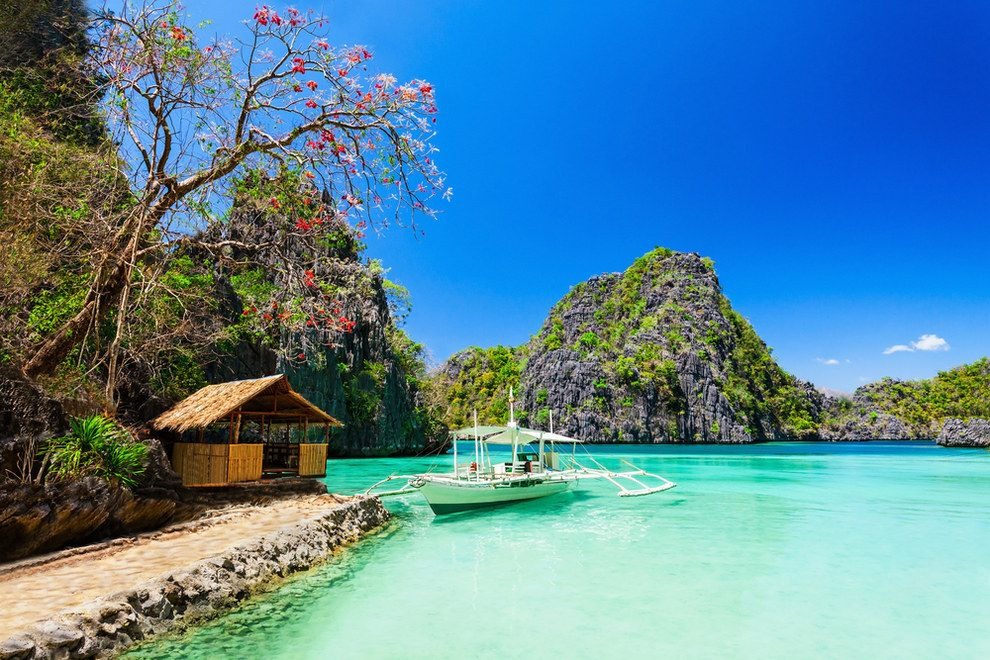 Turquoise water near a sandy shore with a thatched hut in Philippines