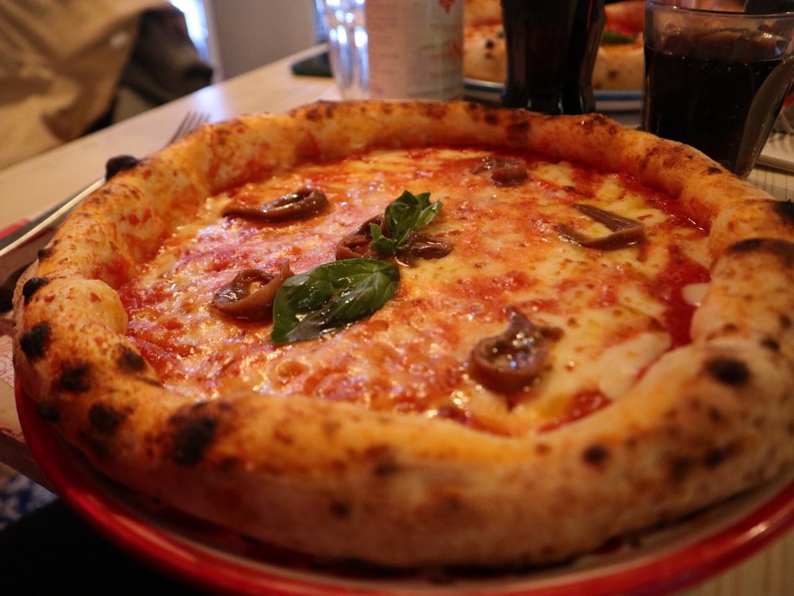 Pizza with mushrooms, mozzarella, and fresh basil on a bubbly crust served on a red plate.